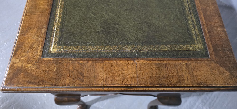 An antique Queen Anne style burr walnut lowboy featuring three drawers, an inset green leather writing top, brass handles, and slender cabriole legs. View XIII