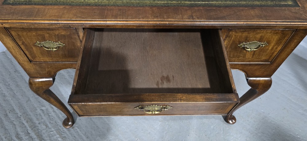 An antique Queen Anne style burr walnut lowboy featuring three drawers, an inset green leather writing top, brass handles, and slender cabriole legs. View XV