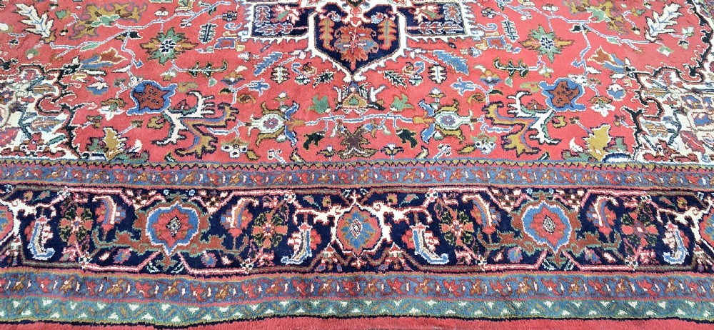 A hand-knotted wool area carpet featuring a large geometric star medallion on a terracotta field with dark navy floral borders and cream fringes. View VIII