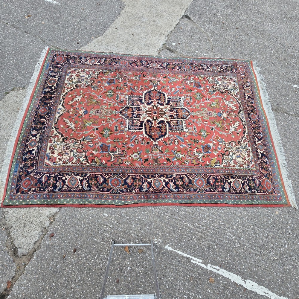 A hand-knotted wool area carpet featuring a large geometric star medallion on a terracotta field with dark navy floral borders and cream fringes. View XI