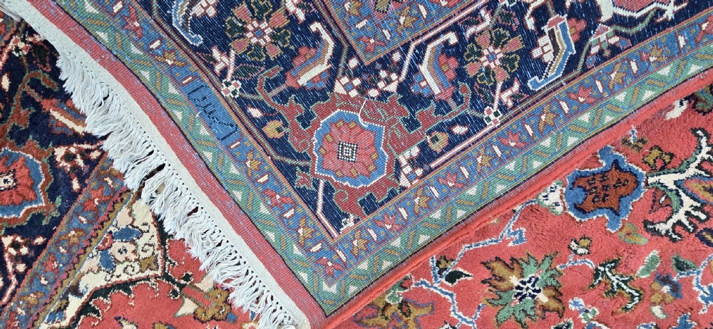 A hand-knotted wool area carpet featuring a large geometric star medallion on a terracotta field with dark navy floral borders and cream fringes. View XII