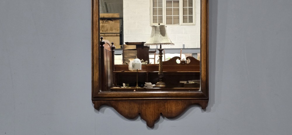 A portrait wall mirror in a dark walnut timber frame featuring an arched top and a carved scallop shell cresting. View IV