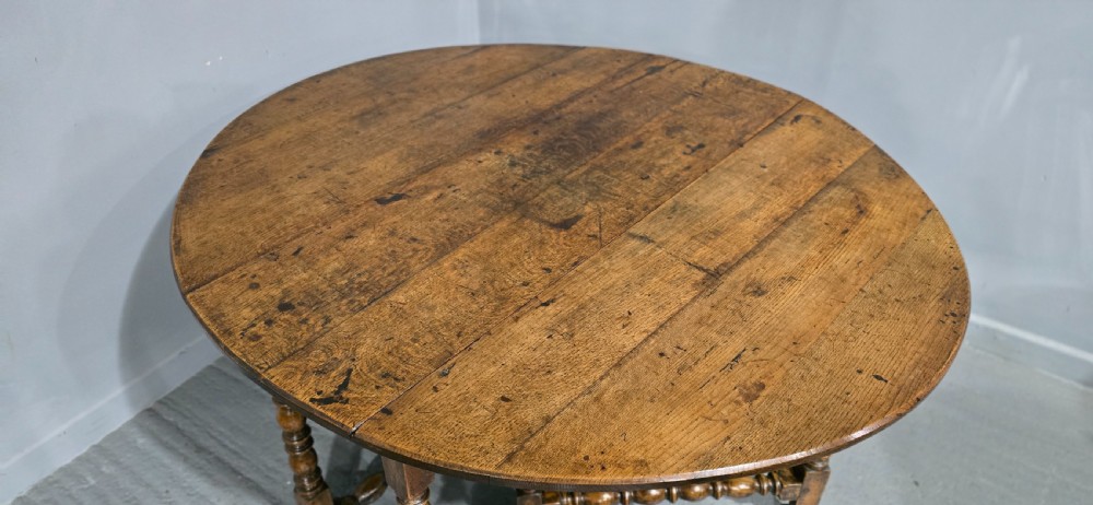 An 18th-century oak drop-leaf dining table featuring turned legs, lower stretchers, and a carved end frieze. View VI