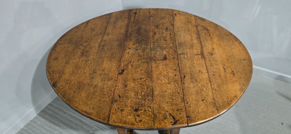 An 18th-century oak drop-leaf dining table featuring turned legs, lower stretchers, and a carved end frieze. View VIII
