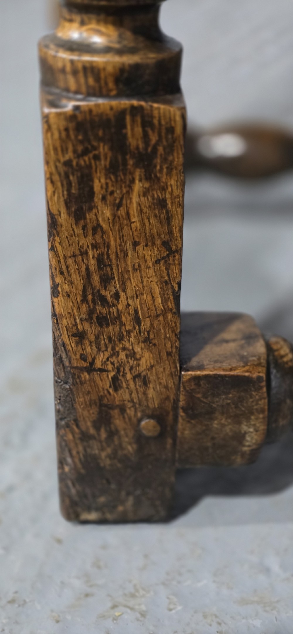 An 18th-century oak drop-leaf dining table featuring turned legs, lower stretchers, and a carved end frieze. View XVI