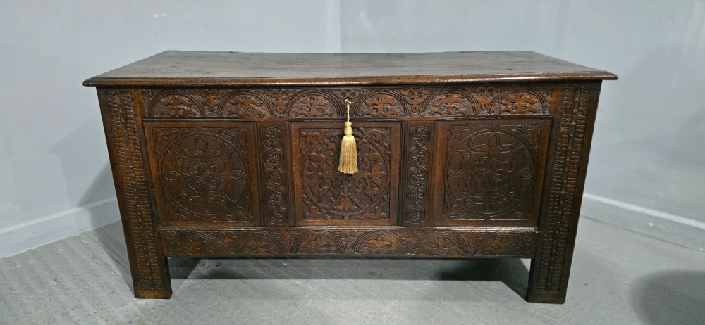 A 17th-century dark oak coffer with three hand-carved front panels and a flat rectangular hinged top. View III