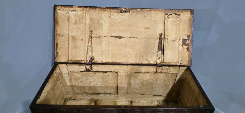 A 17th-century dark oak coffer with three hand-carved front panels and a flat rectangular hinged top. View VII