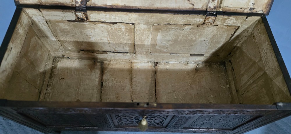 A 17th-century dark oak coffer with three hand-carved front panels and a flat rectangular hinged top. View VIII