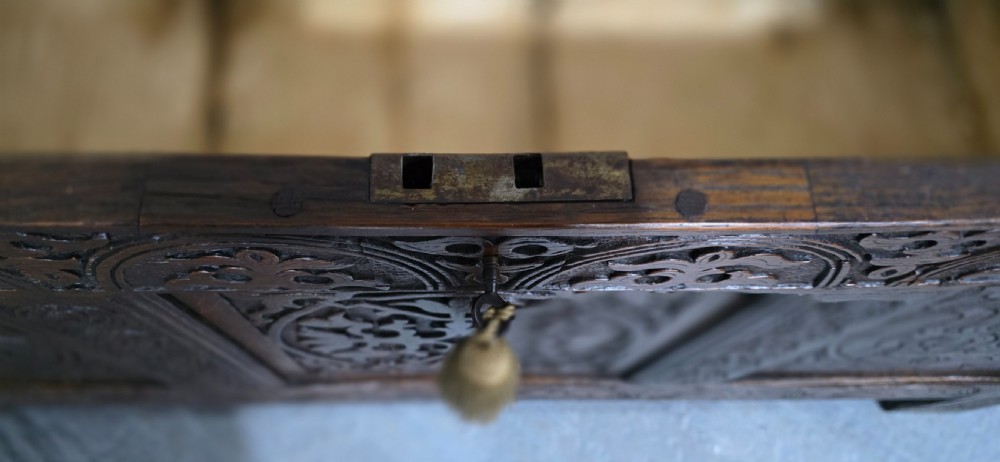 A 17th-century dark oak coffer with three hand-carved front panels and a flat rectangular hinged top. View X