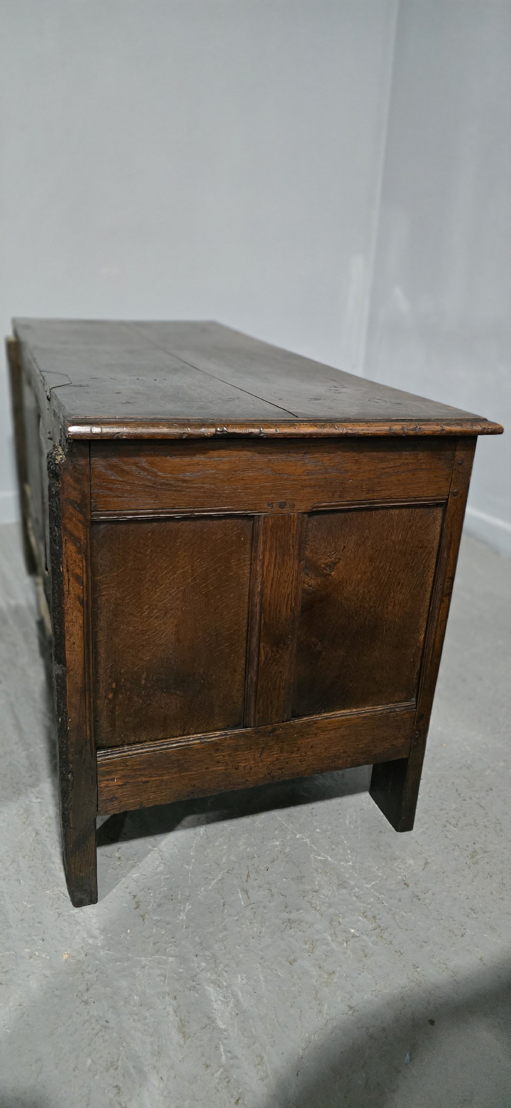A 17th-century dark oak coffer with three hand-carved front panels and a flat rectangular hinged top. View XI