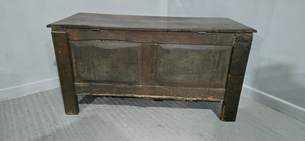 A 17th-century dark oak coffer with three hand-carved front panels and a flat rectangular hinged top. View XII