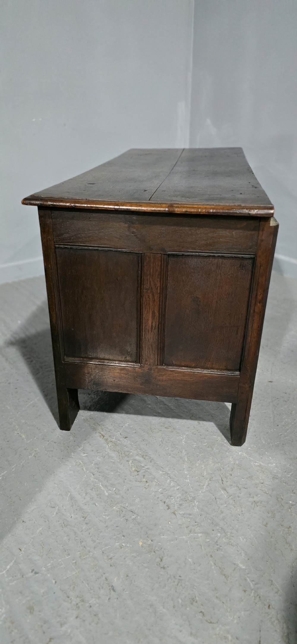 A 17th-century dark oak coffer with three hand-carved front panels and a flat rectangular hinged top. View XIII