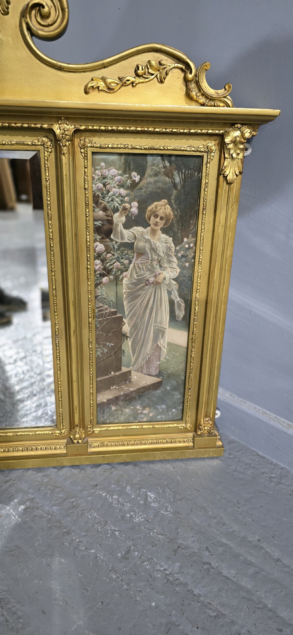 An Edwardian giltwood overmantel mirror featuring a central rectangular glass panel flanked by two vertical printed panels depicting classic female figures in garden settings. View III
