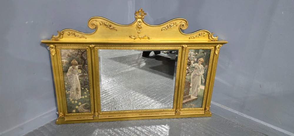 An Edwardian giltwood overmantel mirror featuring a central rectangular glass panel flanked by two vertical printed panels depicting classic female figures in garden settings. View V