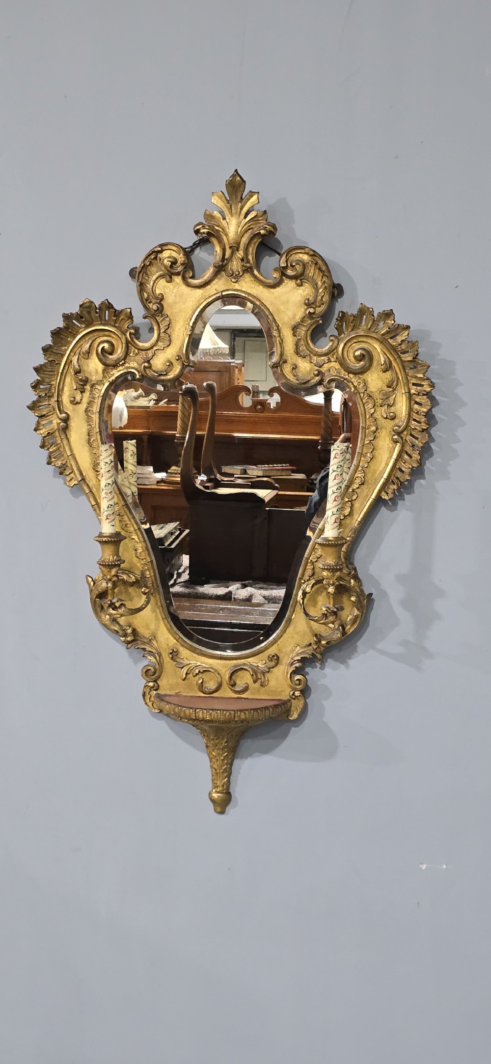 An ornate gold giltwood girandole wall mirror featuring carved Rococo scrollwork and twin integrated candle sconces. View II
