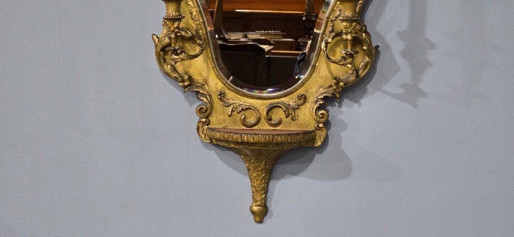 An ornate gold giltwood girandole wall mirror featuring carved Rococo scrollwork and twin integrated candle sconces. View III