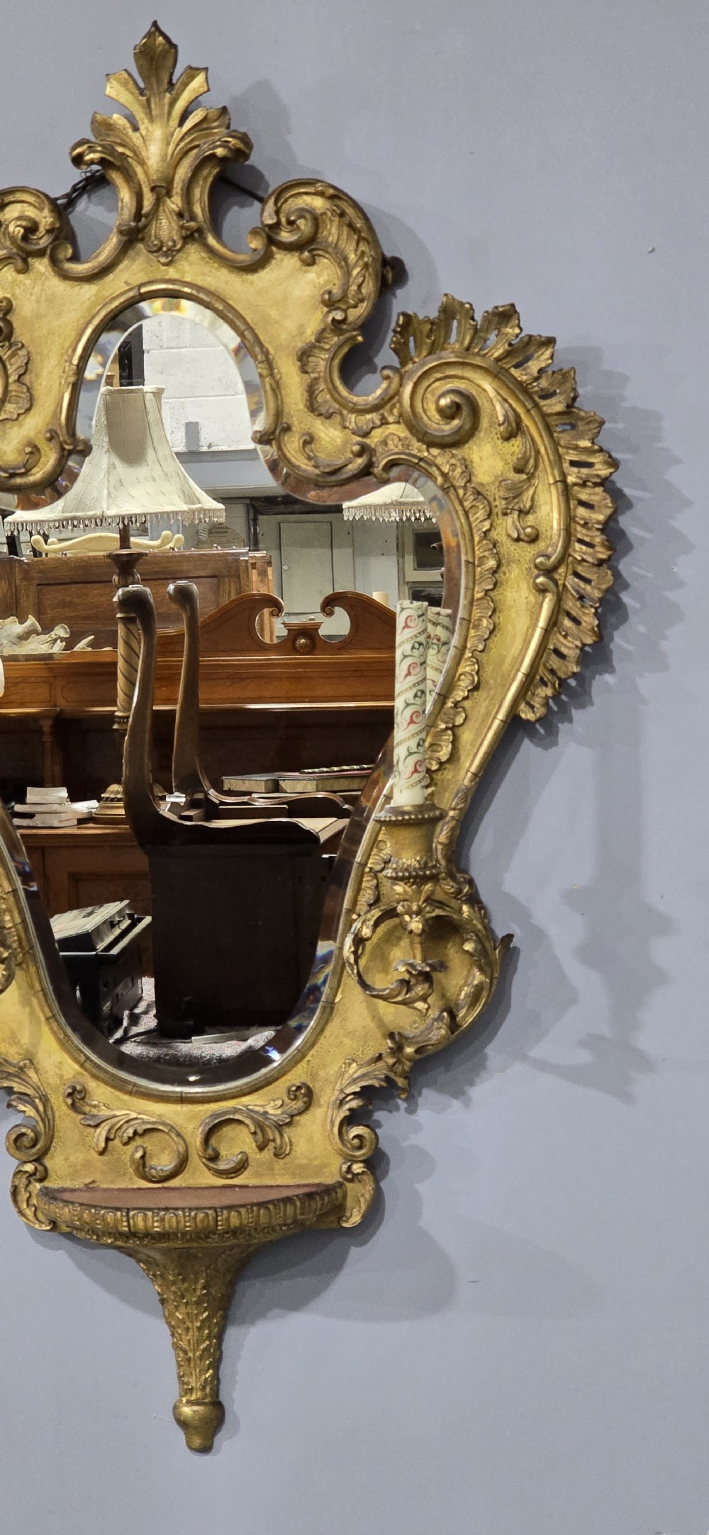 An ornate gold giltwood girandole wall mirror featuring carved Rococo scrollwork and twin integrated candle sconces. View V