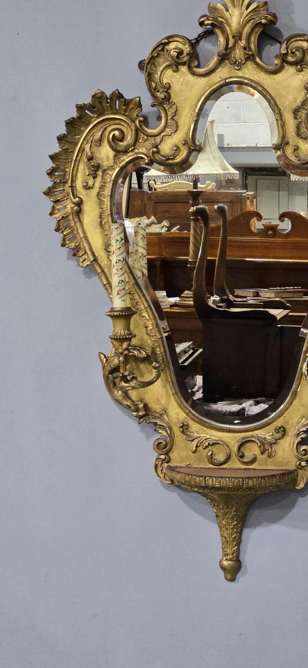 An ornate gold giltwood girandole wall mirror featuring carved Rococo scrollwork and twin integrated candle sconces. View VII