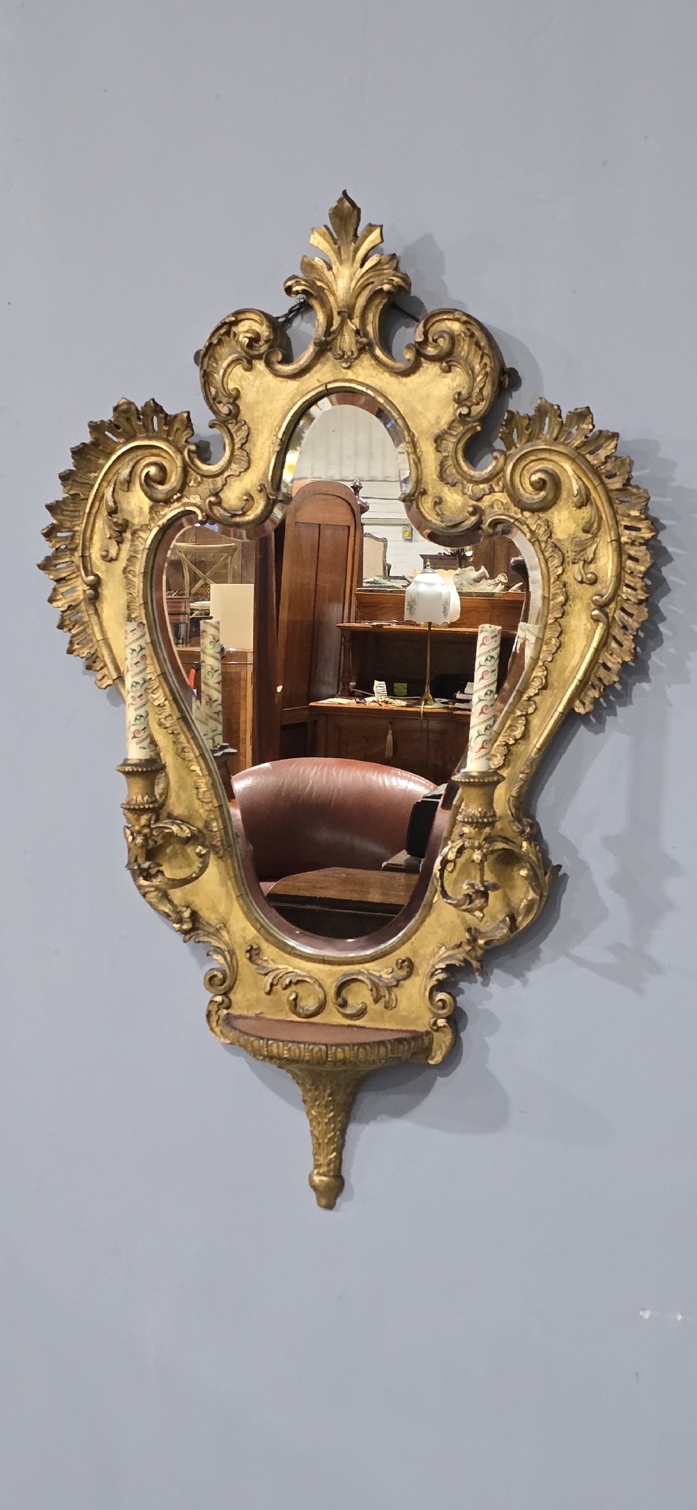An ornate gold giltwood girandole wall mirror featuring carved Rococo scrollwork and twin integrated candle sconces. View IX