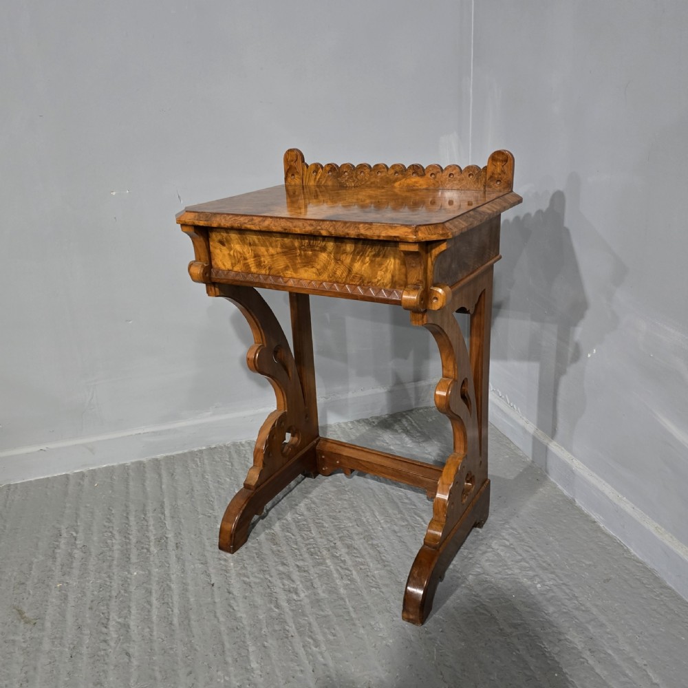 A Victorian burr walnut console table featuring a scalloped gallery back, rich burr veneer top, and carved shaped support legs connected by a central stretcher.