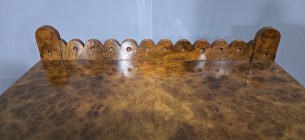 A Victorian burr walnut console table featuring a scalloped gallery back, rich burr veneer top, and carved shaped support legs connected by a central stretcher. View IX