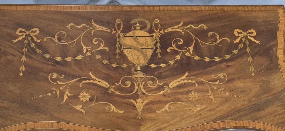 An antique mahogany card table featuring detailed marquetry inlay, a serpentine front, an ornamental urn motif, and square tapered legs. View V