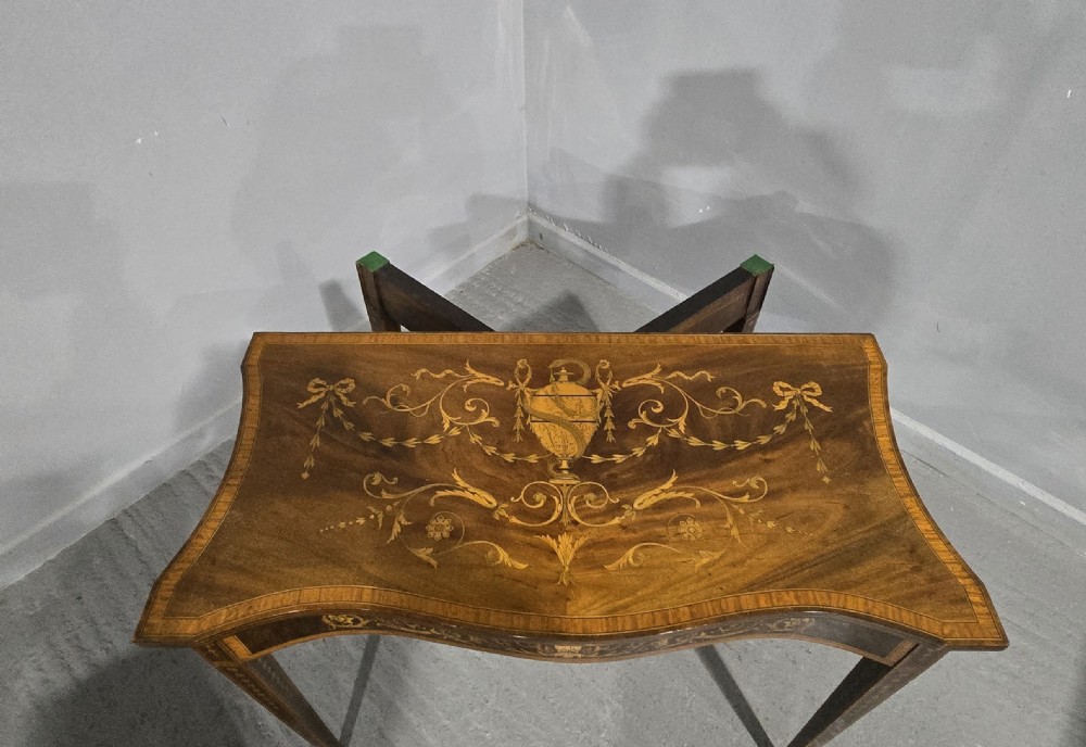An antique mahogany card table featuring detailed marquetry inlay, a serpentine front, an ornamental urn motif, and square tapered legs. View XV