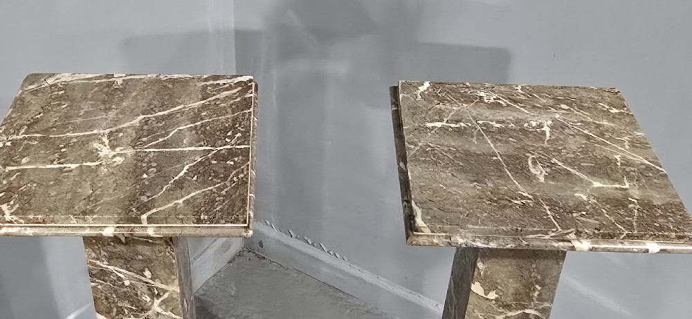 A pair of tall French rouge marble columns with square stepped capital tops, black marble collars, and square plinth bases. View VII