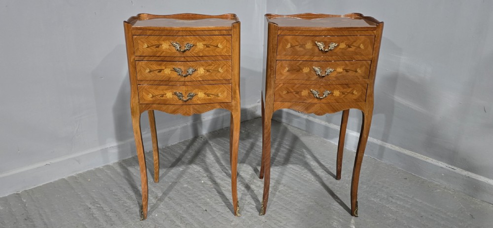 A pair of French marquetry bedside chests with three drawers, floral wood inlays, cabriole legs, and brass handles. View II