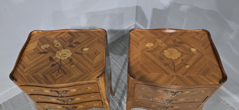 A pair of French marquetry bedside chests with three drawers, floral wood inlays, cabriole legs, and brass handles. View VI