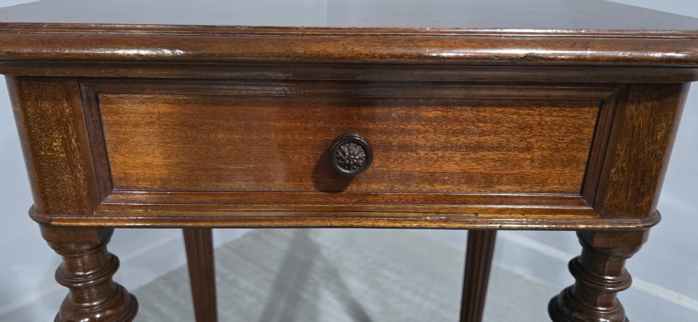 A Victorian mahogany lamp table featuring a single drawer with a round brass knob, four fluted turned legs, and a lower rectangular shelf. View III
