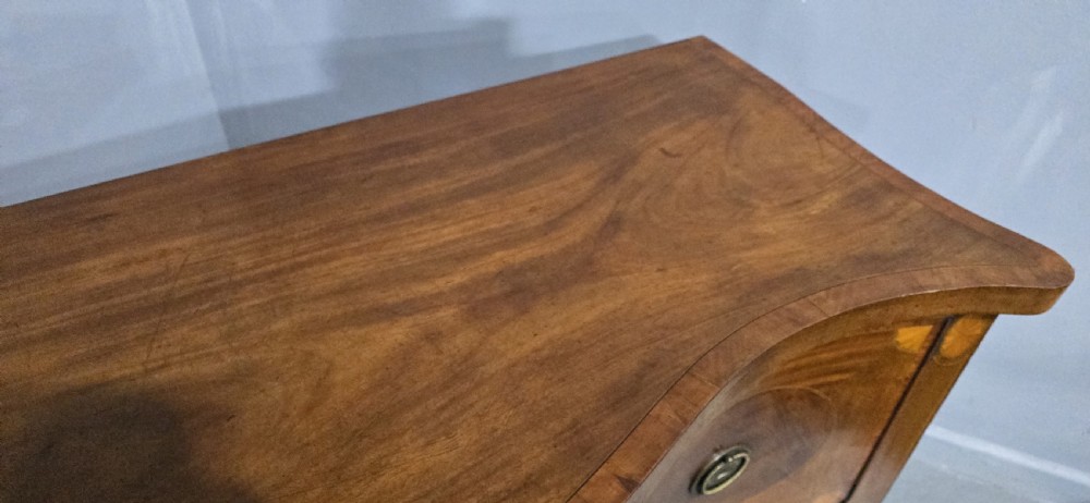 An Edwardian inlaid mahogany sideboard with oval panel doors, central drawers, brass ring handles, and square tapered legs. View X