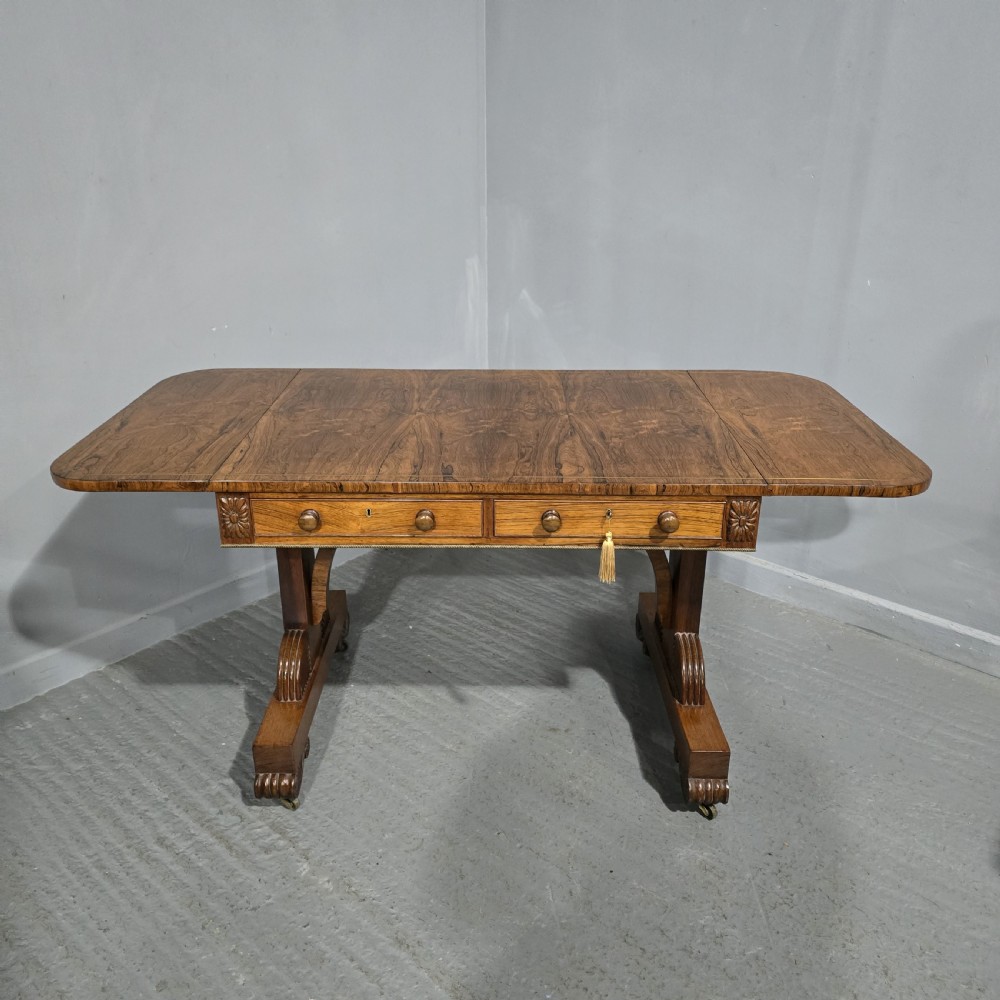 A Regency rosewood sofa table with two frieze drawers, brass line inlay, drop leaves, carved rosette corners, and reeded legs on brass castors. View III