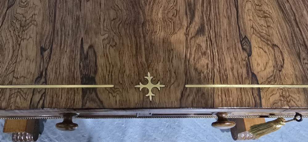 A Regency rosewood sofa table with two frieze drawers, brass line inlay, drop leaves, carved rosette corners, and reeded legs on brass castors. View VIII