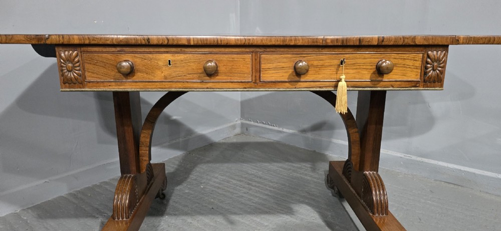 A Regency rosewood sofa table with two frieze drawers, brass line inlay, drop leaves, carved rosette corners, and reeded legs on brass castors. View XI