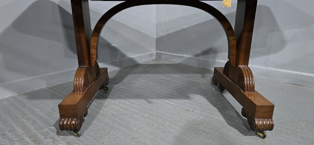 A Regency rosewood sofa table with two frieze drawers, brass line inlay, drop leaves, carved rosette corners, and reeded legs on brass castors. View XIII