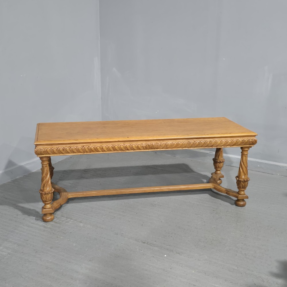 A rectangular carved light oak footboard bench featuring a gadrooned edge, turned twist legs with acanthus leaf details, and a lower connecting stretcher.