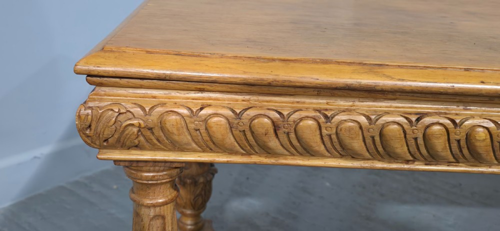A rectangular carved light oak footboard bench featuring a gadrooned edge, turned twist legs with acanthus leaf details, and a lower connecting stretcher. View V