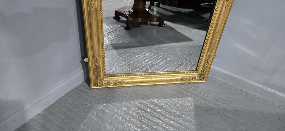 A large rectangular antique giltwood pier mirror featuring rounded top corners, beaded inner borders, and floral relief moulding along the gold frame. View V
