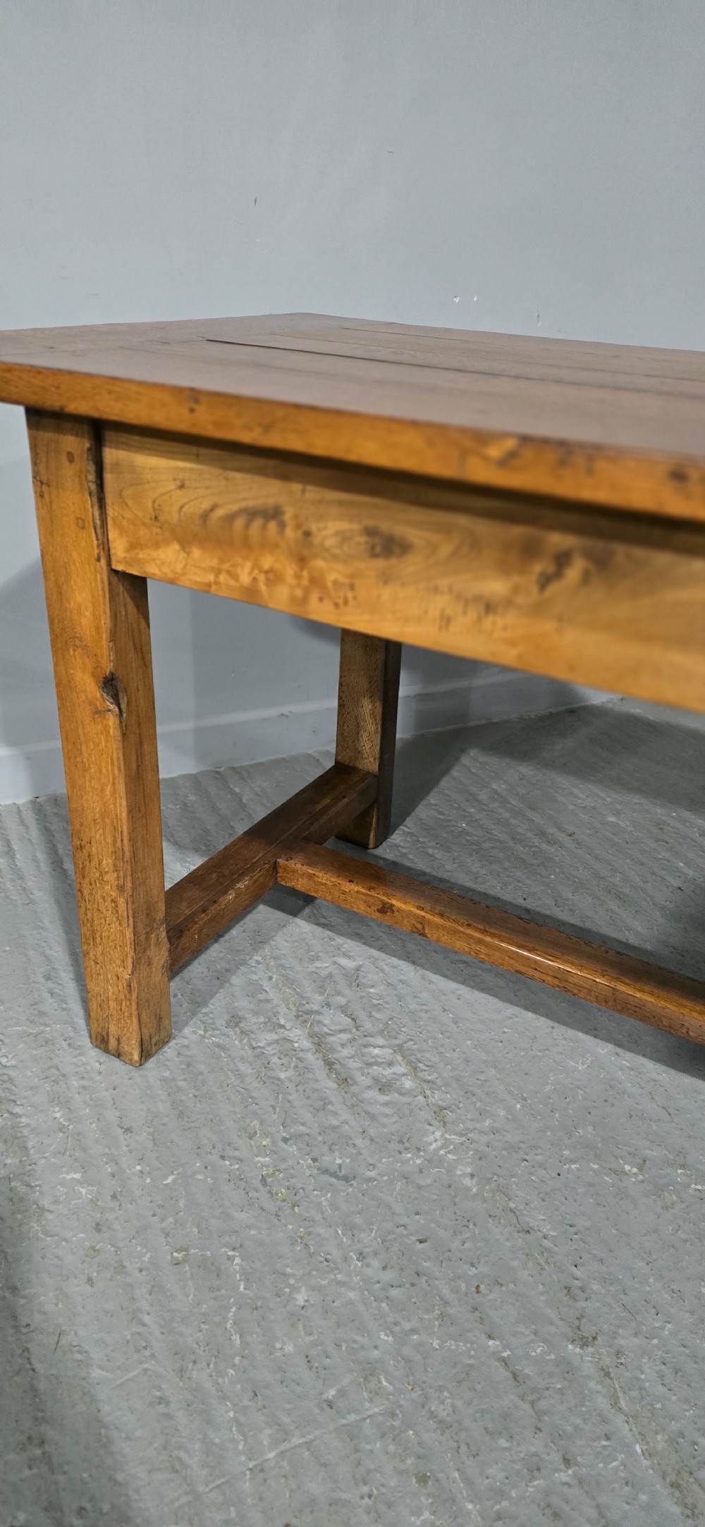 A long wooden French farmhouse refectory dining table featuring a central frieze drawer and lower stretcher bar. View V