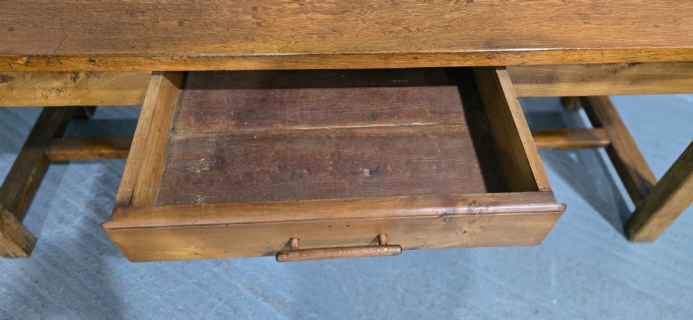 A long wooden French farmhouse refectory dining table featuring a central frieze drawer and lower stretcher bar. View VI