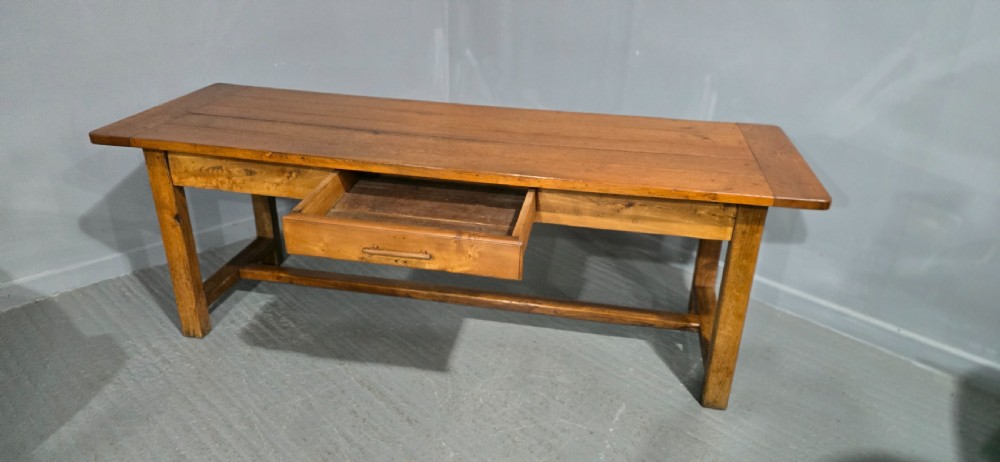 A long wooden French farmhouse refectory dining table featuring a central frieze drawer and lower stretcher bar. View VII