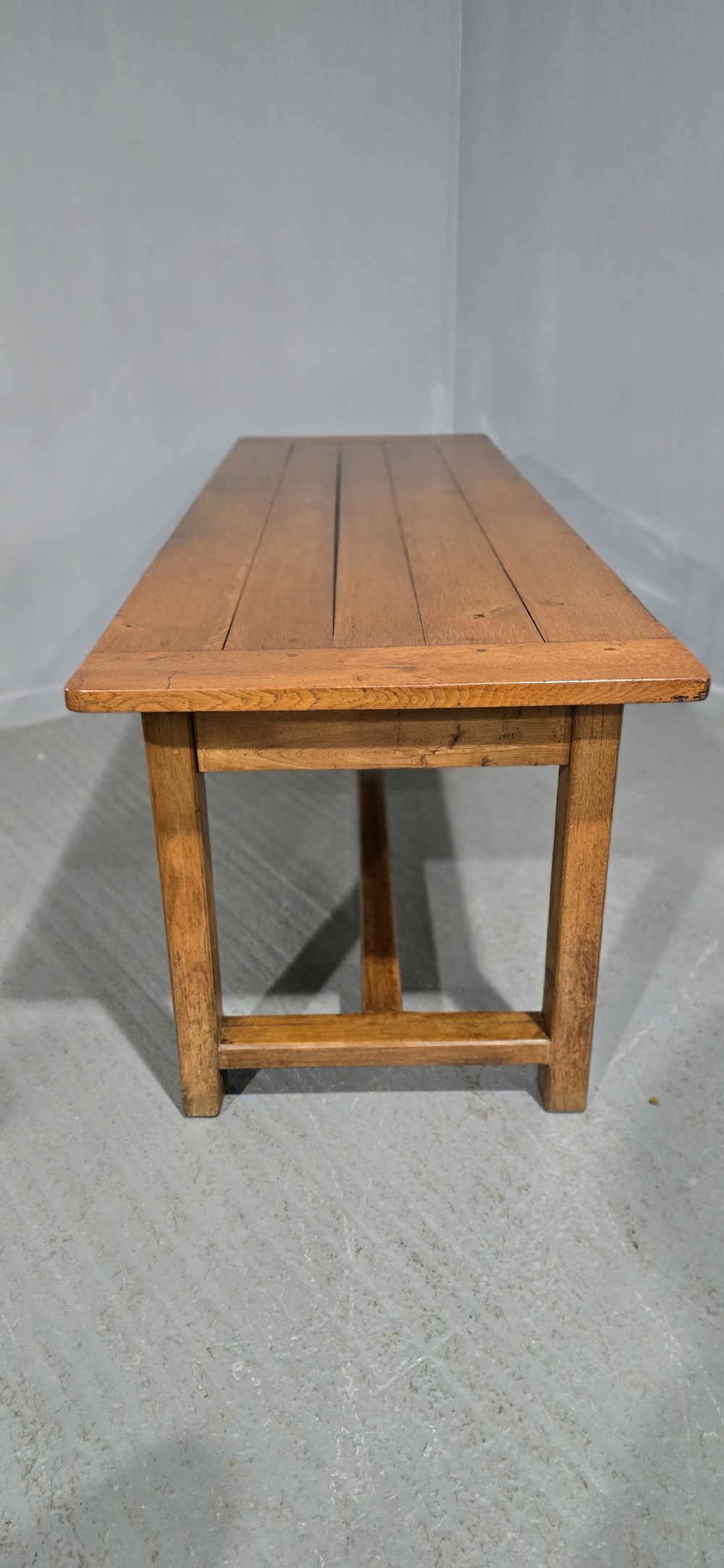 A long wooden French farmhouse refectory dining table featuring a central frieze drawer and lower stretcher bar. View XI