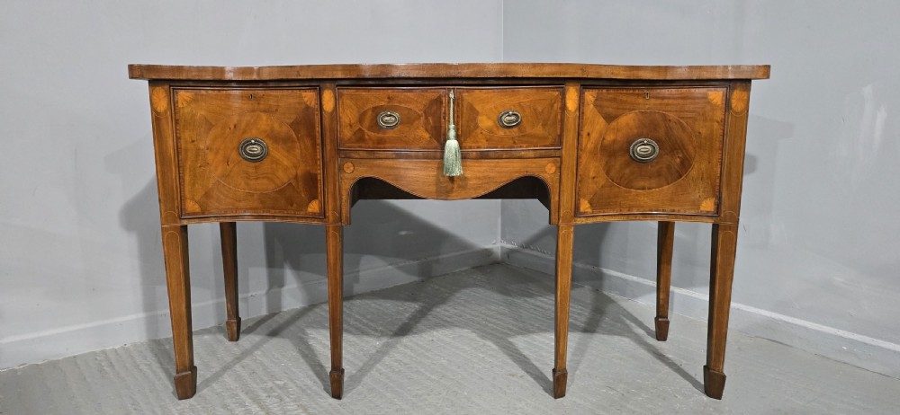 An Edwardian mahogany sideboard featuring satinwood inlay, oval fan motifs, central drawers, flanking cupboards, and slender tapered legs. View II