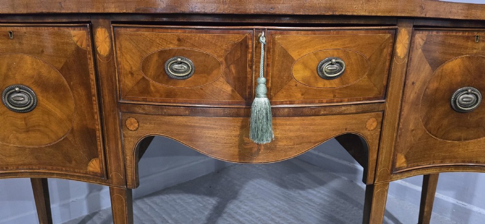 An Edwardian mahogany sideboard featuring satinwood inlay, oval fan motifs, central drawers, flanking cupboards, and slender tapered legs. View III