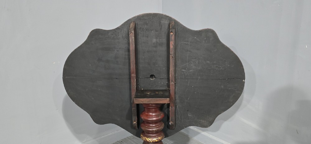 An Italian painted tilt-top side table featuring a dark burgundy ground decorated with a central hand-painted floral bouquet and gilt scrollwork borders. View V