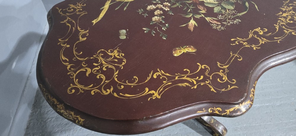 An Italian painted tilt-top side table featuring a dark burgundy ground decorated with a central hand-painted floral bouquet and gilt scrollwork borders. View XX