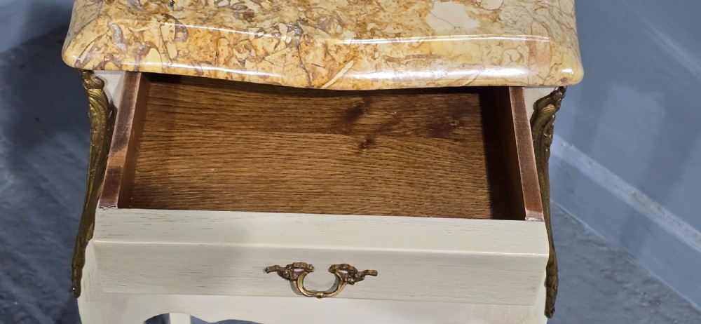 A pair of slender cream-painted French Louis style bedside chests featuring shaped marble tops, three drawers, and decorative brass mounts on tall cabriole legs. View VIII
