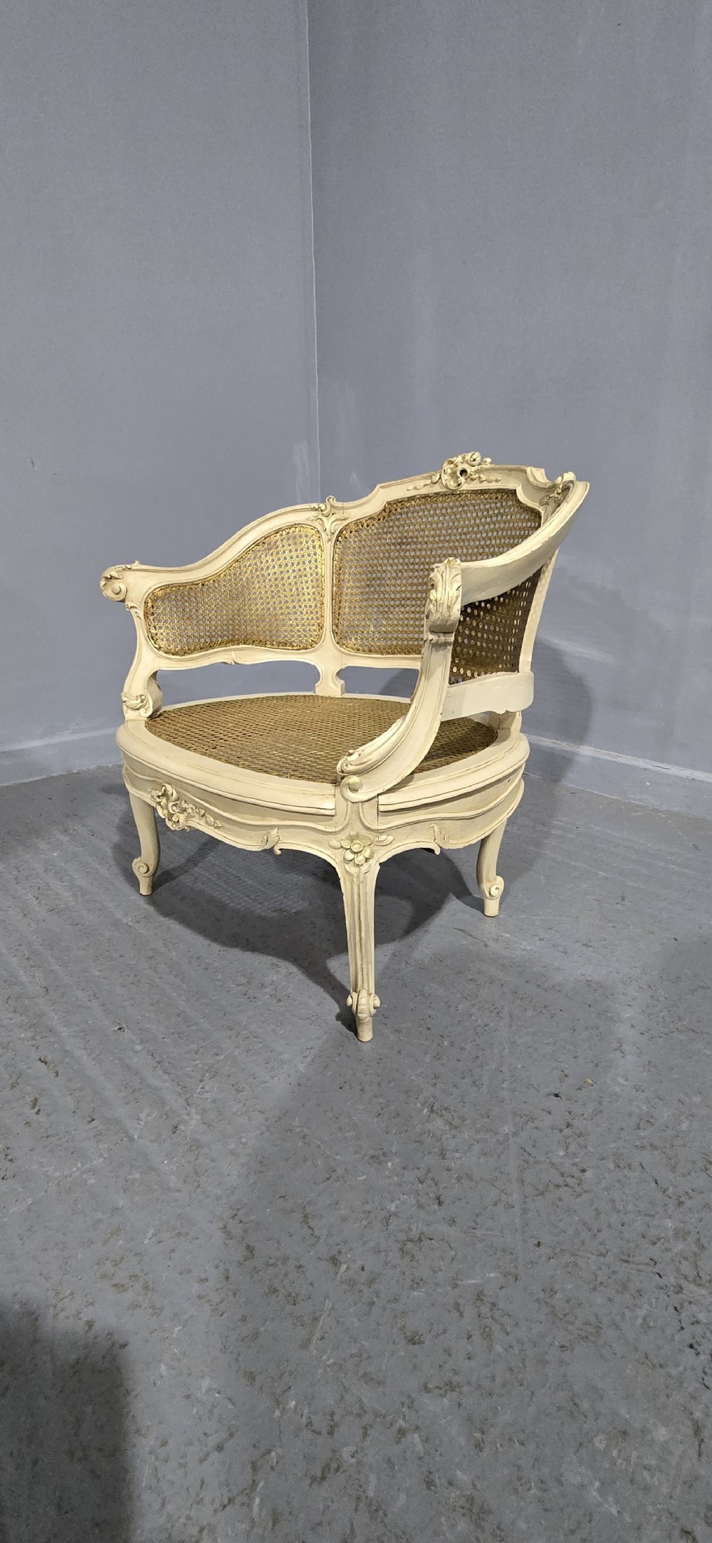 A French Louis XV style cream painted and gilded tub armchair featuring a carved wooden frame with hand-woven rattan cane back, sides, and seat on cabriole legs. View III