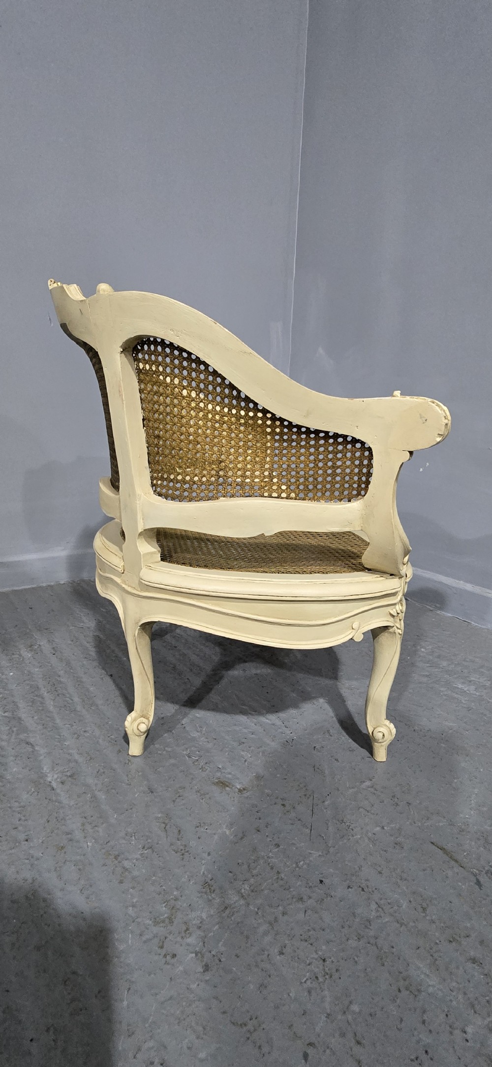A French Louis XV style cream painted and gilded tub armchair featuring a carved wooden frame with hand-woven rattan cane back, sides, and seat on cabriole legs. View V